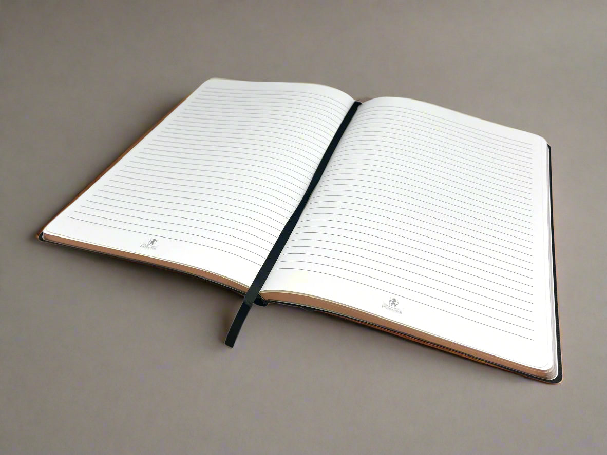 A Highlander Black B5 Journal lying open with a black satin page marker in the middle on a taupe background