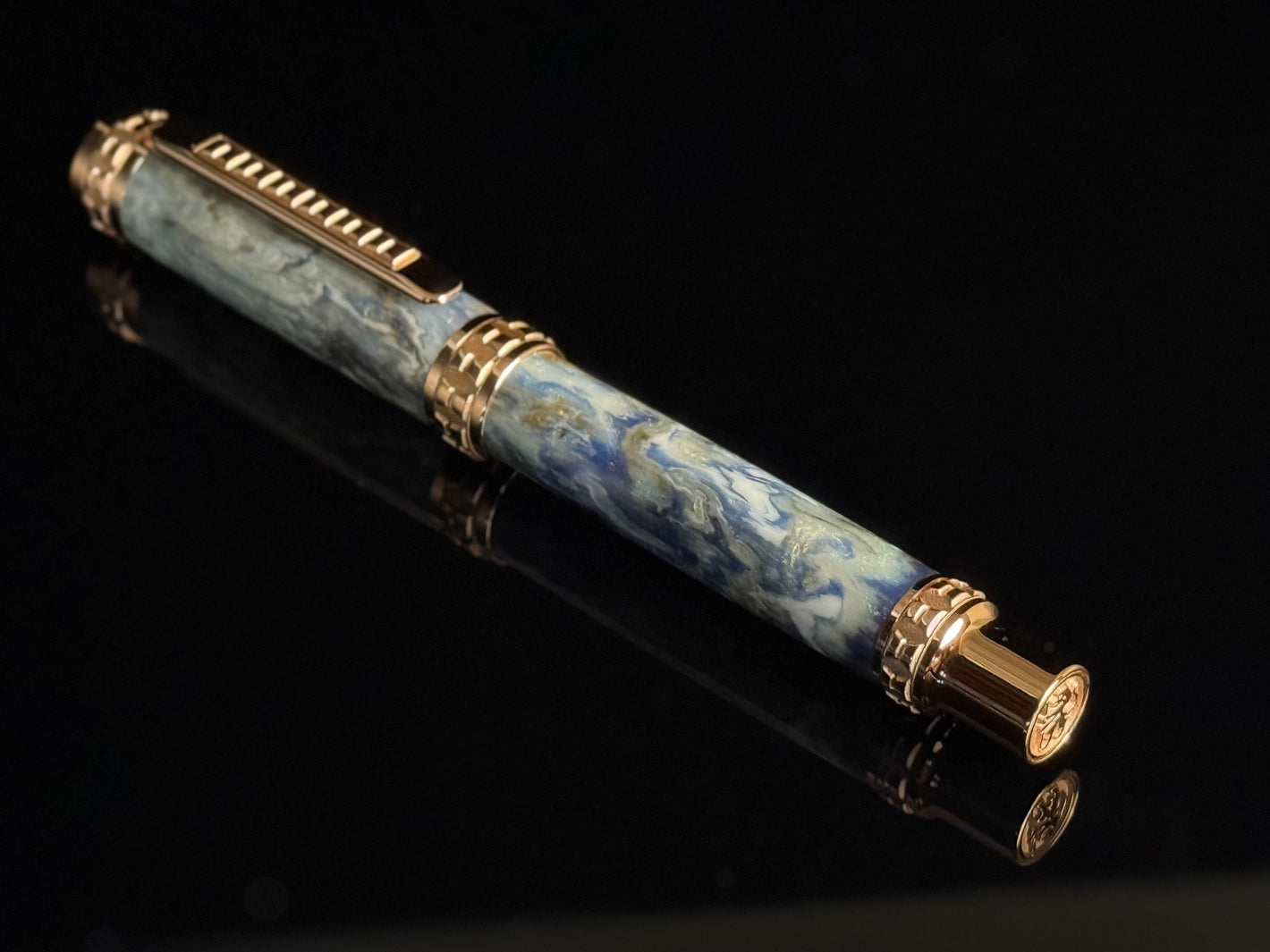 Luxury pen with blue marble pattern and gold accents on a black background